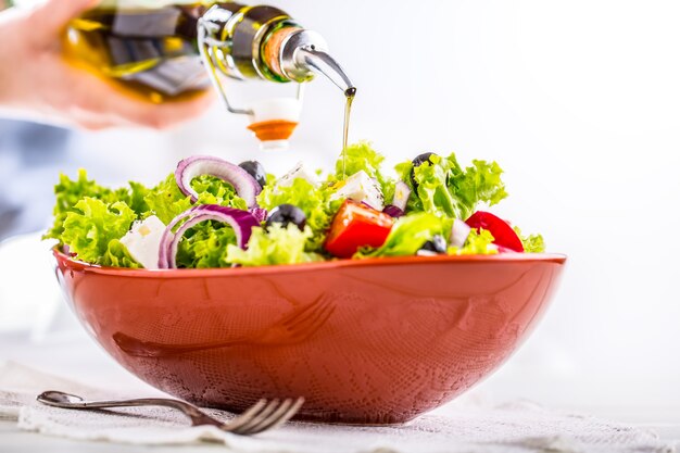 Salada de vegetais frescos com tomate cebola queijo e azeitonas Azeite servindo na tigela de salada