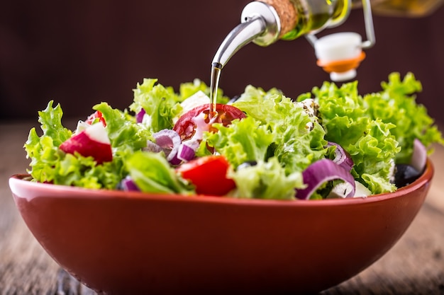 Salada de vegetais frescos com tomate cebola queijo e azeitonas azeite servindo na tigela de salada