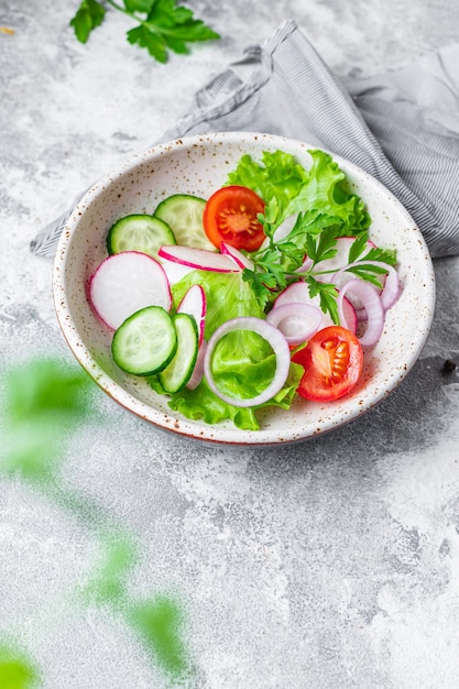 salada de vegetais saudáveis tomate, pepino, porção de alface mistura de rabanete na mesa