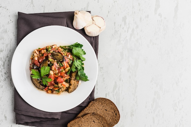 Salada de verão de berinjela e tomate em um prato branco