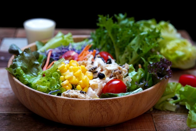 Salada de verduras mistas de frango cozido em uma tigela de madeira