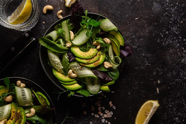 Salada de verduras, pepino e abacate em uma mesa escura. prato vegetariano