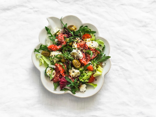 Salada deliciosa com vegetais salmão levemente salgado azeitonas mozzarella em um fundo claro vista de cima