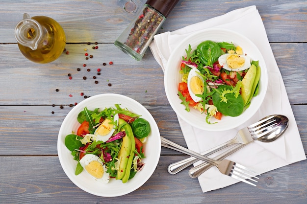 Salada deliciosa e leve de tomates, ovos e uma mistura de folhas de alface. Café da manhã saudável
