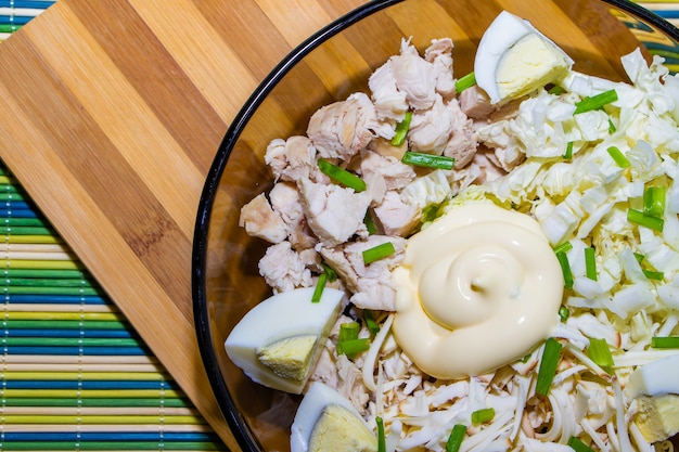 Salada dietética para uma nutrição adequada com frango e ovos em um tapete verde.