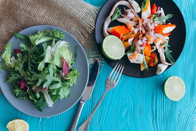 Salada e macarrão com frutos do mar em um fundo azul