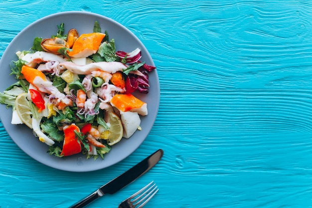 Salada e macarrão com frutos do mar em um fundo azul