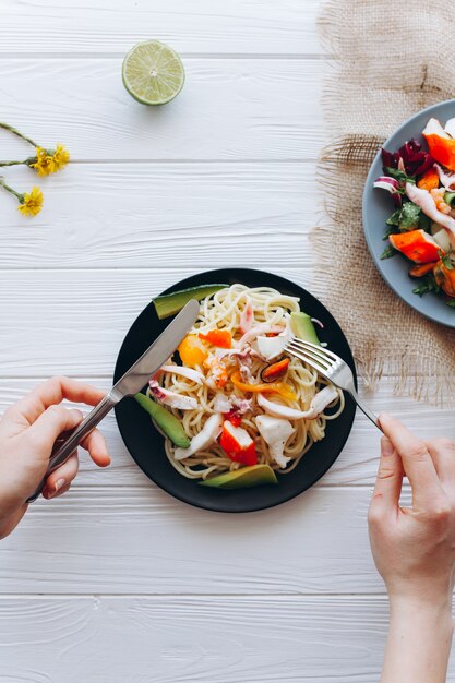 Salada e macarrão com frutos do mar no fundo branco