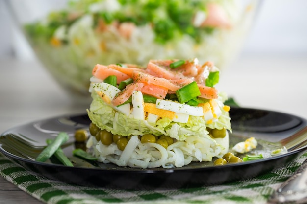 Salada em camadas de repolho e outros vegetais com pedaços de peixe vermelho em um prato