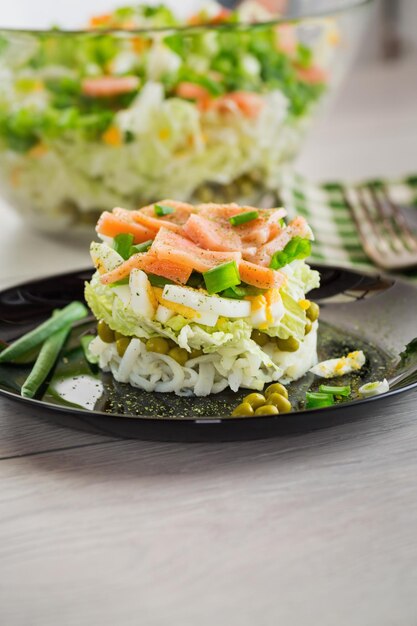 Salada em camadas de repolho e outros vegetais com pedaços de peixe vermelho em um prato