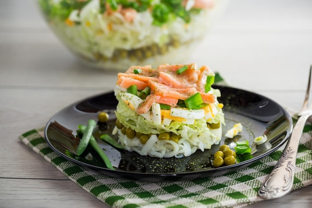 Salada em camadas de repolho e outros vegetais com pedaços de peixe vermelho em um prato