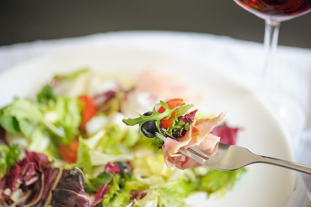 Salada em um garfo no fundo de um prato com salada