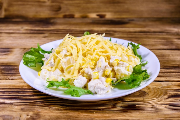 Salada festiva com peito de frango, abacaxi em conserva, queijo, milho doce e maionese em mesa de madeira rústica
