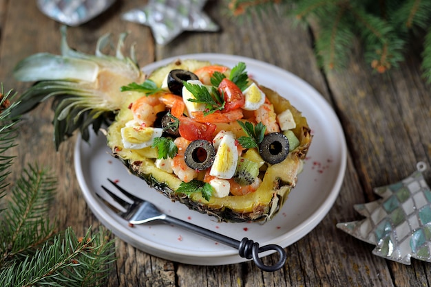 Salada festiva de camarão, kiwi, azeitonas, queijo macio, ovos de codorna, tomate cereja em pratos de abacaxi.