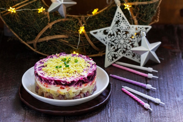 Salada festiva soviética tradicional de arenque vestido de arenque e legumes em uma decoração de ano novo