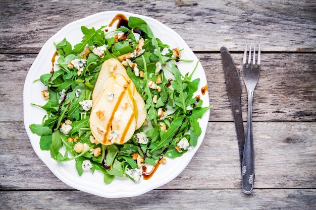 Salada fresca com nozes de pera rúcula e queijo azul em fundo de madeira