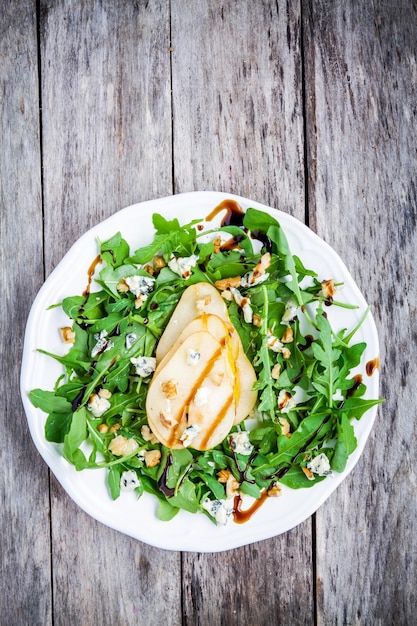 Salada fresca com nozes de pera rúcula e queijo azul em fundo de madeira