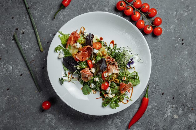 Salada fresca com presunto e pêra em um fundo cinza escuro