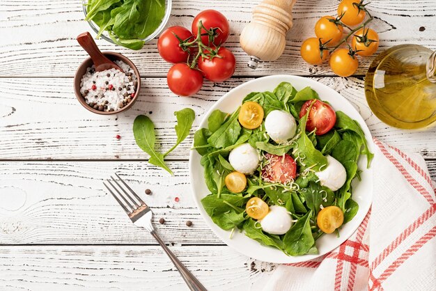 Salada fresca com queijo mussarela de tomate cereja rúcula e queijo duro sobre fundo branco de madeira Vista superior