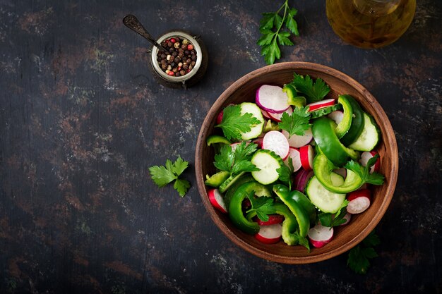 Salada fresca de pepinos, rabanetes, pimentão verde e salsa. Lay plana. Vista do topo