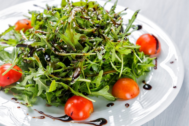 Salada fresca de tomate cereja, alface, beniseed e molho num prato branco