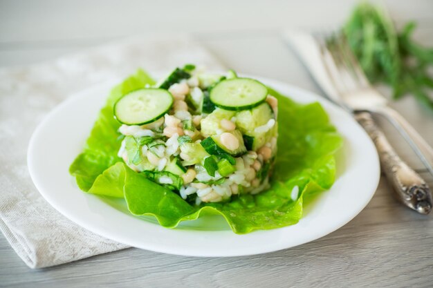 salada fresca de verão com feijão, arroz, pepino e outros vegetais em um prato sobre uma mesa de madeira