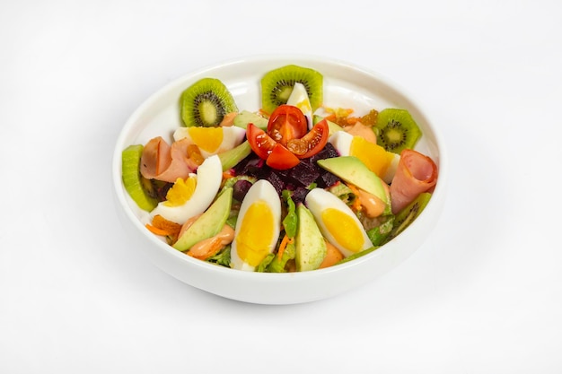 Salada fresca feita com ovos de abacate de kiwi frescos misturados com legumes na tigela branca fundo branco