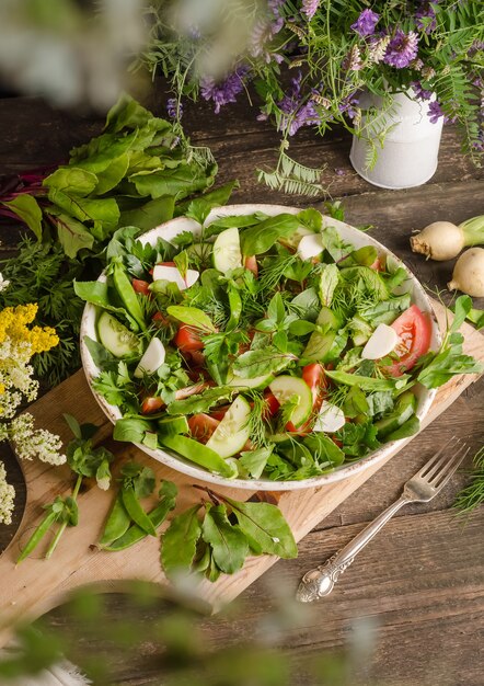 Foto salada fresca misturada com uma variedade de ervas, tomates, pepinos, vagens de ervilha verde