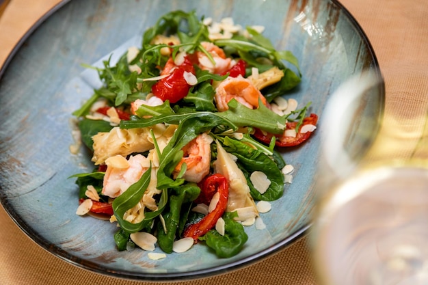 Salada fresca servida com um copo de vinho servido mesa