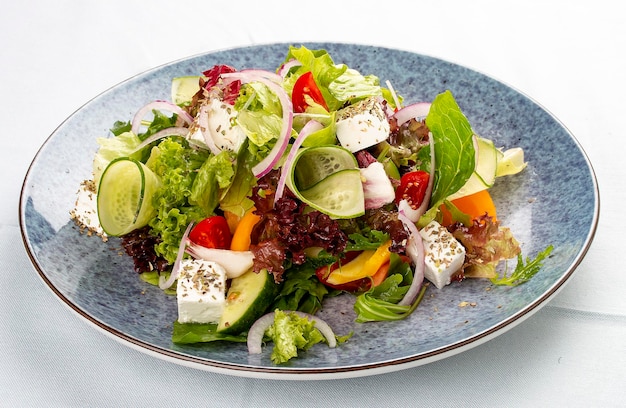 Salada grega clássica de tomates pepinos cebolas de pimenta vermelha com azeitonas orégano e queijo feta Num prato decorativo