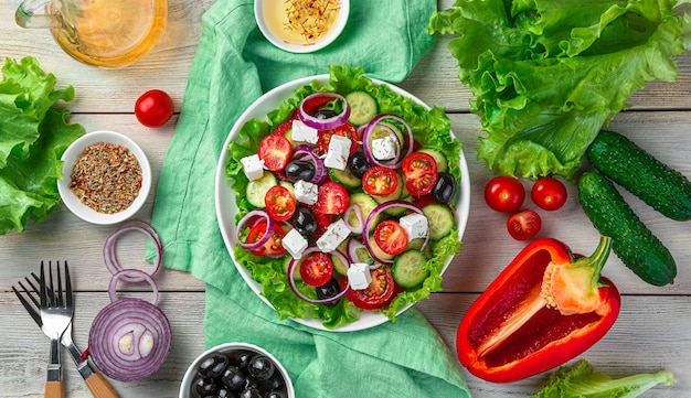 Salada grega colorida e deliciosa sobre um fundo claro de madeira com ingredientes. vista superior, horizontal. o conceito de origens culinárias.