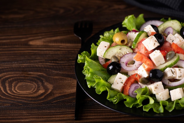 Salada grega com azeitonas e alcaparras em prato preto