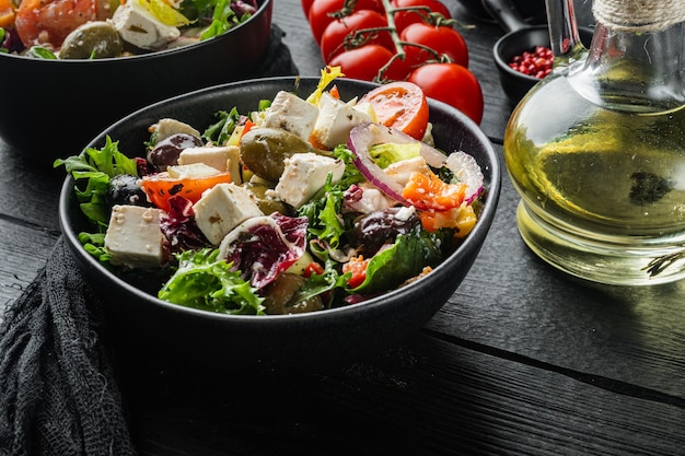 Foto salada grega com legumes frescos, queijo feta e azeitonas kalamati, em mesa de madeira preta