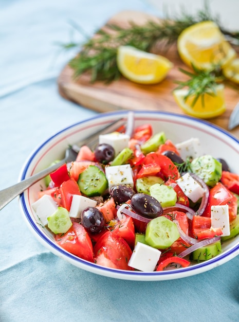 Salada grega com queijo feta azeitonas tomate pepino e cebola vermelha dieta mediterrânea vegetariana saudável alimentos com poucas calorias comer fundo de tecido azul vista superior