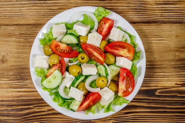 Salada grega com queijo feta de legumes frescos e azeitonas verdes na mesa de madeira Vista superior