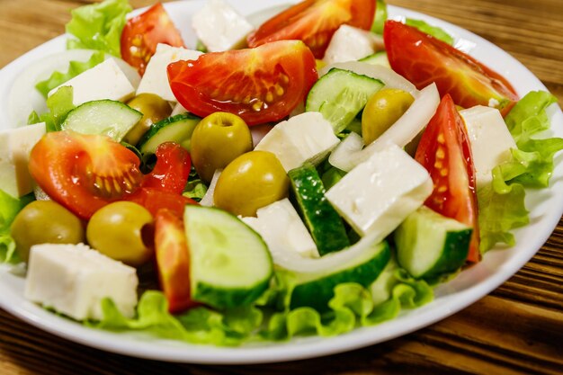 Salada grega com queijo feta de legumes frescos e azeitonas verdes na mesa de madeira