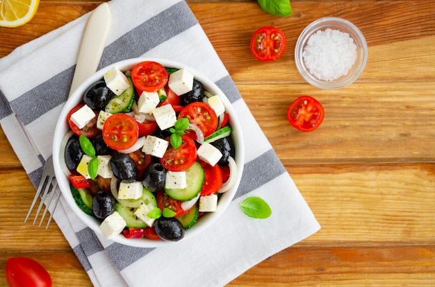 Salada grega de vegetais frescos e suculentos, queijo feta, ervas e azeitonas em uma tigela branca. Comida saudável.