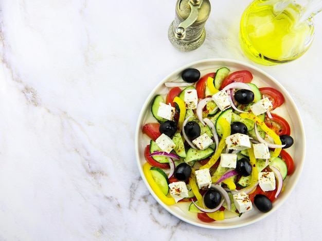 Salada grega em um prato sobre um fundo de mármore cinza. Prato do restaurante. Salada de legumes com azeite