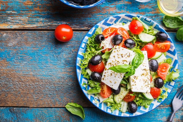 Salada grega fresca de pepino, tomate, pimentão, cebola roxa, queijo feta e azeitonas com azeite. Comida saudável, vista de cima