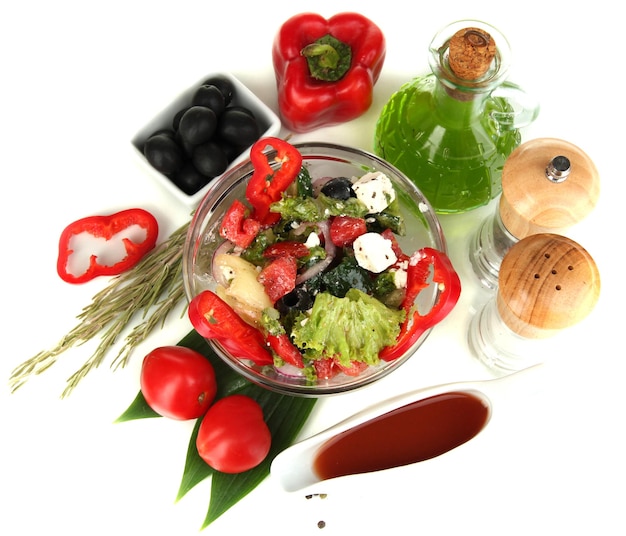Foto salada grega fresca em tigela de vidro cercada por ingredientes para cozinhar isolados em branco