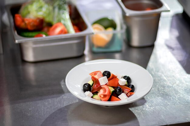 Salada grega recém-preparada em um prato branco está na mesa da cozinha Conceito de embeber salada vegetariana