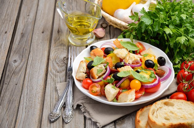 Salada italiana tradicional de Panzanella com tomates frescos e pão crocante na mesa de madeira rústica.