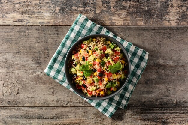 Salada mexicana com quinua em uma tigela na mesa de madeira