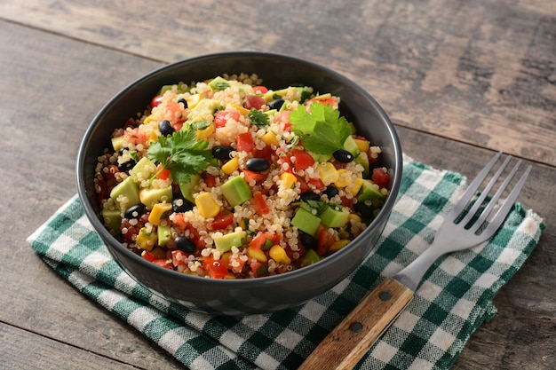 Salada mexicana com quinua em uma tigela na mesa de madeira