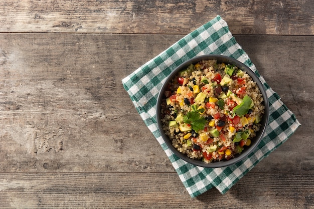 Salada mexicana com quinua em uma tigela na mesa de madeira