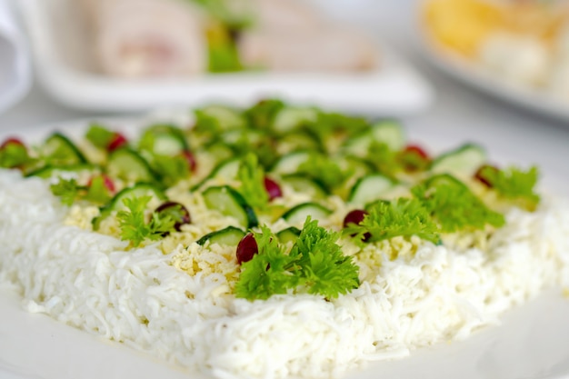 Salada Mimosa guarnecido com pepinos fatiados e raminhos de salsa.