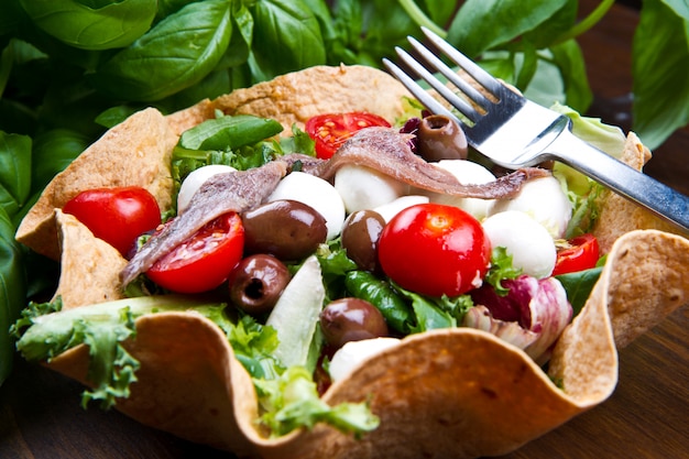 salada mista com mussarela e anchova em uma cesta de pão