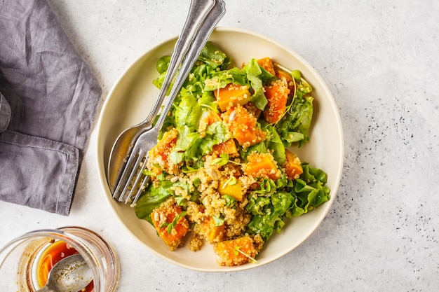 Salada morna do quinoa e da abóbora em uma placa branca, vista superior, espaço da cópia.