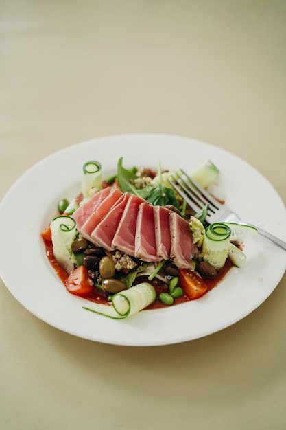 salada nicoise em um prato branco com um garfo