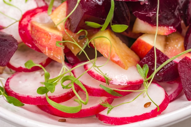 Salada nutritiva de beterraba cozida fatiada, rabanete fatiado e maçãs com brotos microgreen jovens.